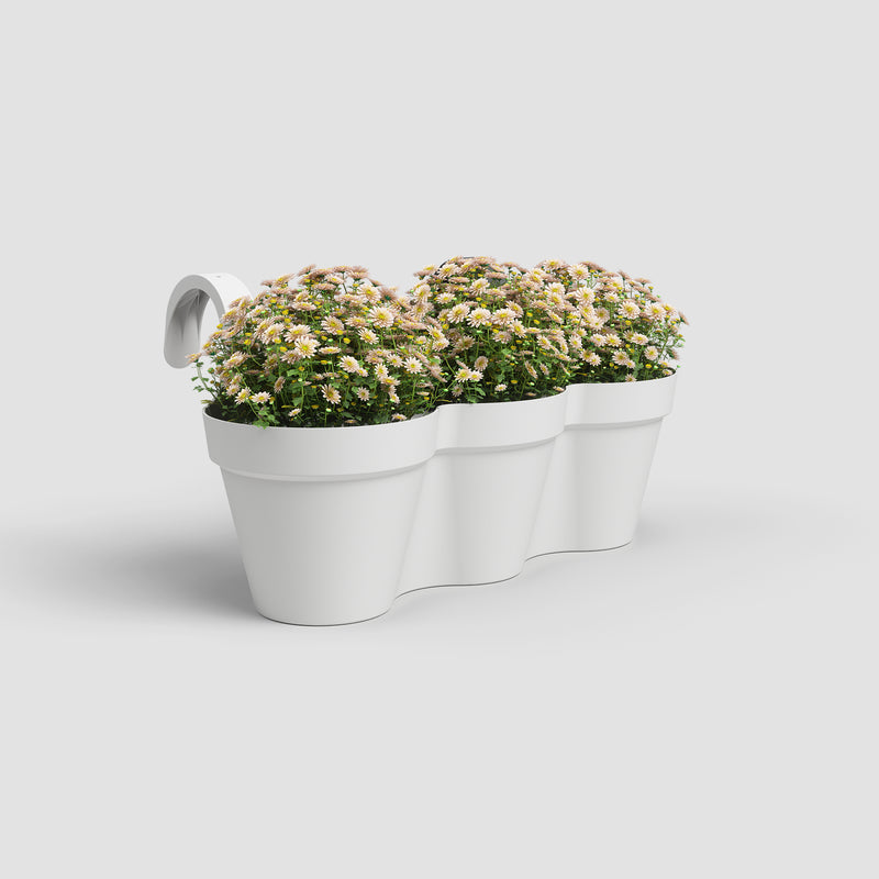 White three- compartment planter with flowers on a light gray background