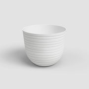 White ceramic planter with ribbed texture on a light gray background