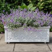 Decorative white planter with purple flowers on a stone patio