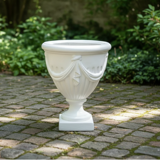 Decorative white urn on a stone patio with greenery in the background