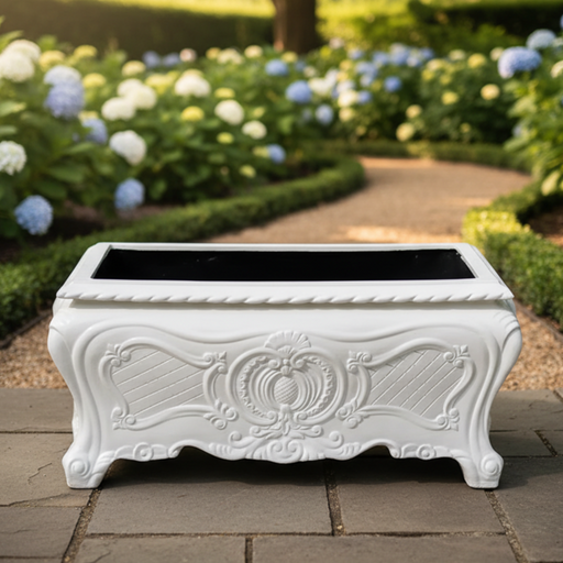 Decorative white planter with intricate designs on a stone path in a garden setting.