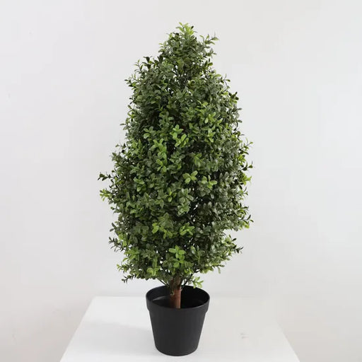 Potted artificial tree on a white surface with a light gray background