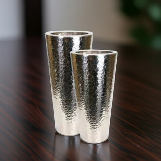 Two silver hammered metal vases on a dark wooden surface